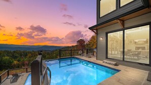 Une maison moderne dotée d’une piscine, de grandes fenêtres et offrant une vue panoramique sur les montagnes.