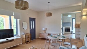Un salon moderne comprenant un téléviseur, un canapé, une table à manger et des chaises.