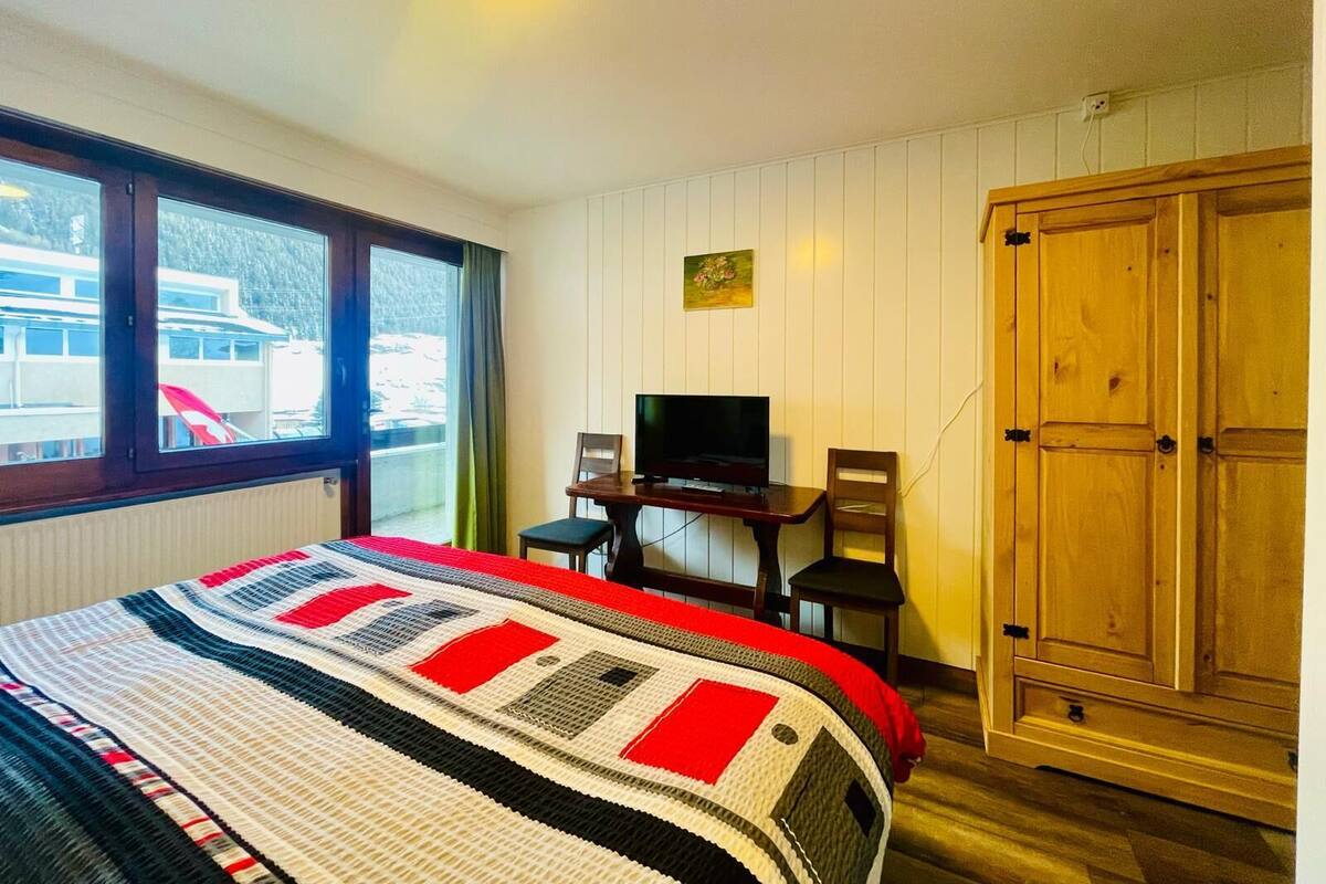 Une chambre d’hôtel avec un lit, un téléviseur posé sur un bureau, une armoire et une fenêtre donnant sur l’extérieur.