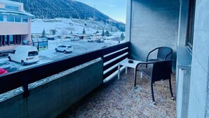 Un balcon donnant sur un paysage enneigé, un fourgon garé et une chaise.