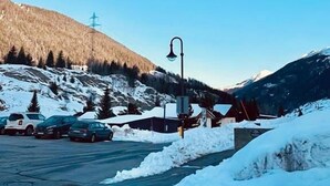 Une enseigne pour l’auberge Les Charmettes, avec un paysage montagneux en arrière-plan.