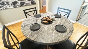 Un coin repas avec une table ronde, des chaises noires et une assiette de pâtisseries.