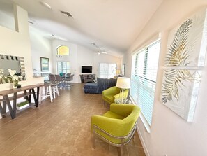 Un amplio espacio de sala con una mesa de comedor, sillas, un sofá y un televisor.
