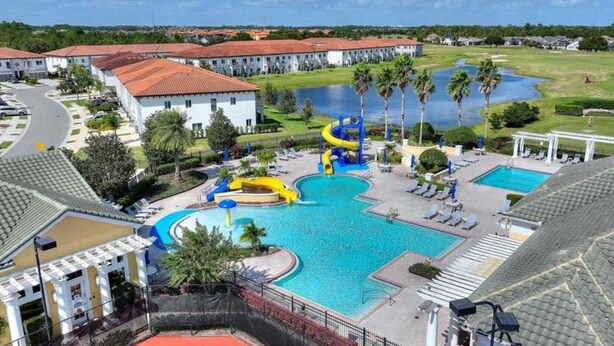 A swimming pool with slides, a golf course, and a building with a red roof.