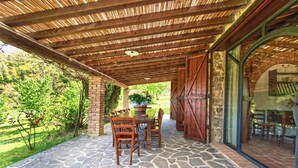 An outdoor patio with stone flooring, wooden furniture, and a covered area with a bamboo roof. - Podere La Marroneta (Tuscany Hills & private Pool) (Rivalto)