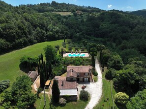 Uma villa com piscina, rodeada por vegetação exuberante e colinas.