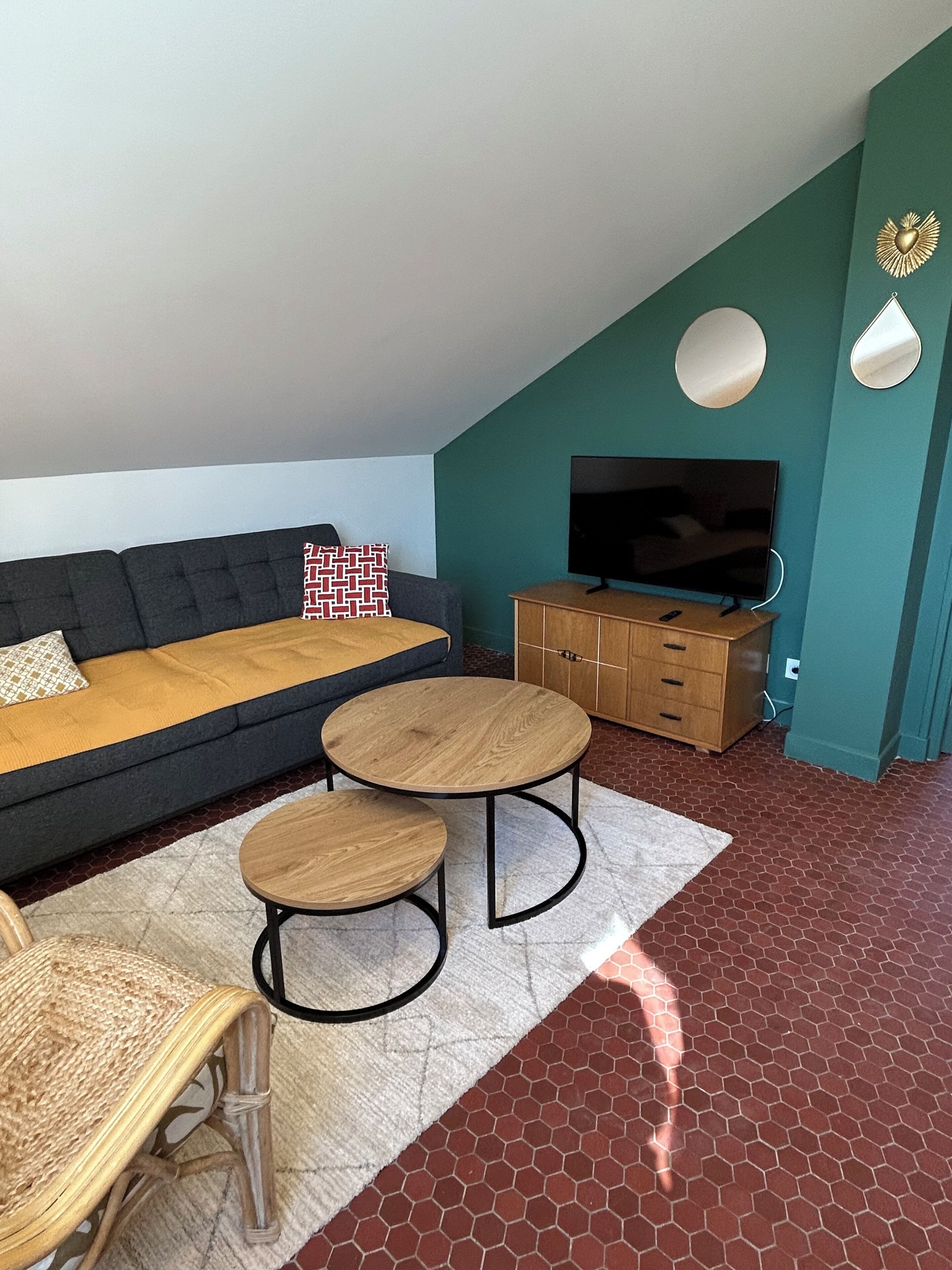 Ein Wohnzimmer mit einem dunklen Sofa, zwei Holztischen, einem Fernseher und einem Schrank.