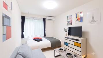 Ein modernes Hotelzimmer mit einem Bett, einer Couch, einem Fernseher und einem Essbereich.