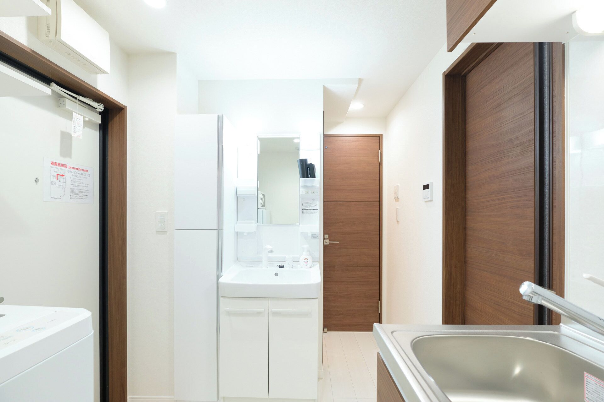 Eine kleine Küche mit Kühlschrank, Spüle und Holztür.