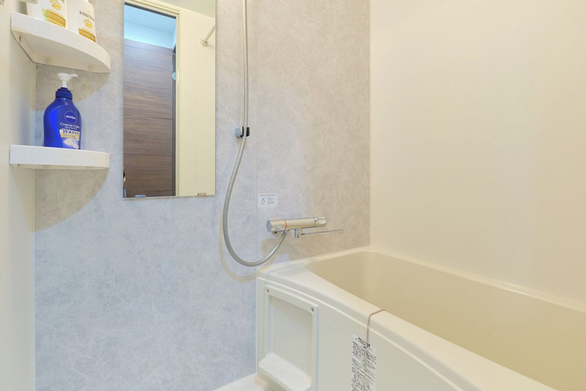 Een badkamer met een badkuip, douche, handdroger en een plank met toiletartikelen.