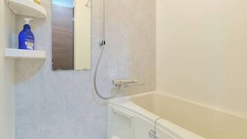 Een badkamer met een badkuip, douche, handdroger en een plank met toiletartikelen.