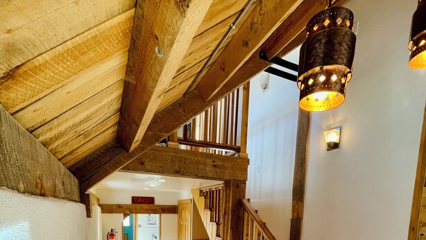 Una escalera de madera con suelo de baldosas que lleva a un segundo nivel.