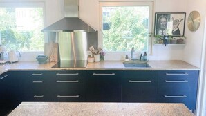 Una cocina moderna con armarios oscuros, una campana extractora de acero inoxidable, encimera de granito y ventana con vistas a zonas verdes.