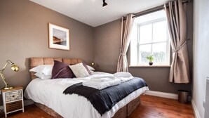 A bedroom with a bed, a nightstand, a lamp, a window with curtains, and a framed picture on the wall. - The Dale Manor, Allendale, Northumberland (Allendale Town)