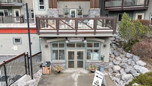 A building with a front desk, outdoor seating, and a sign indicating a front desk location. - Mountains' Edge by ML (Canmore)