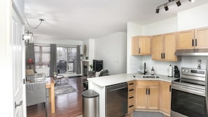 A modern kitchen with wooden cabinets, a built-in oven, and a dining area with a table and chairs. - Mountains' Edge by ML (Canmore)
