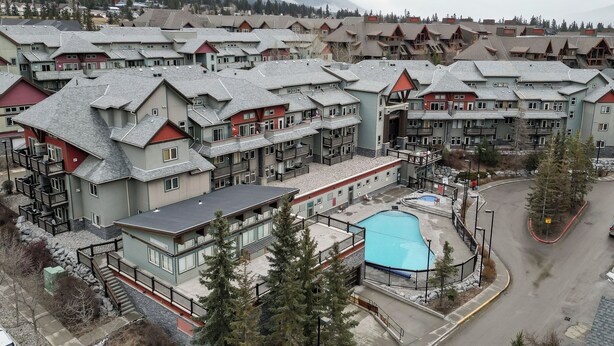 A resort with multiple buildings, a swimming pool, and a mountainous backdrop. - Mountains' Edge by ML (Canmore)