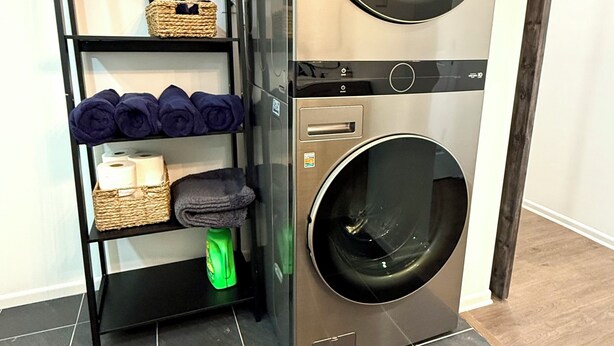 A compact, stainless steel LG washer and dryer unit with a built-in shelf for laundry items.