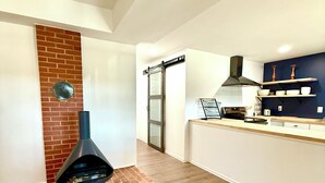 A modern kitchen with a brick accent wall, a built-in oven, and wooden shelves.