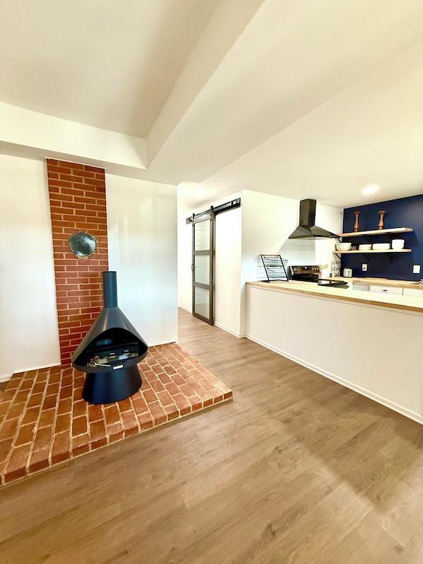 A modern kitchen with a brick accent wall, a built-in oven, and wooden shelves.