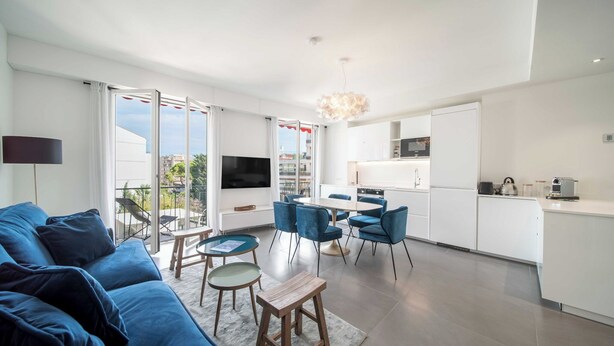 Una sala de estar moderna con un sofá, un televisor y un comedor con sillas y una mesa.