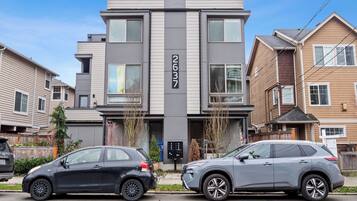En moderne bygning i to etager med en grå facade og et synligt adresseskilt.