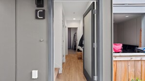 A modern interior with a wooden floor, a kitchen area with a red bag, and a grey wall with a letter 'C'. - Modern Townhome in Walkable Ballard - 2 bedroom, 2 bathroom with AC (Seattle)