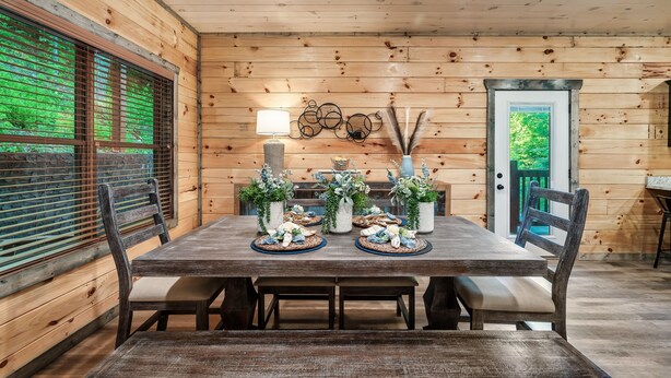 A wooden interior with a dining table set for four, surrounded by chairs. - Modern Cabin with Hot Tub, Air Hockey, King Beds, Grill and Outdoor Pool! (Sevierville)