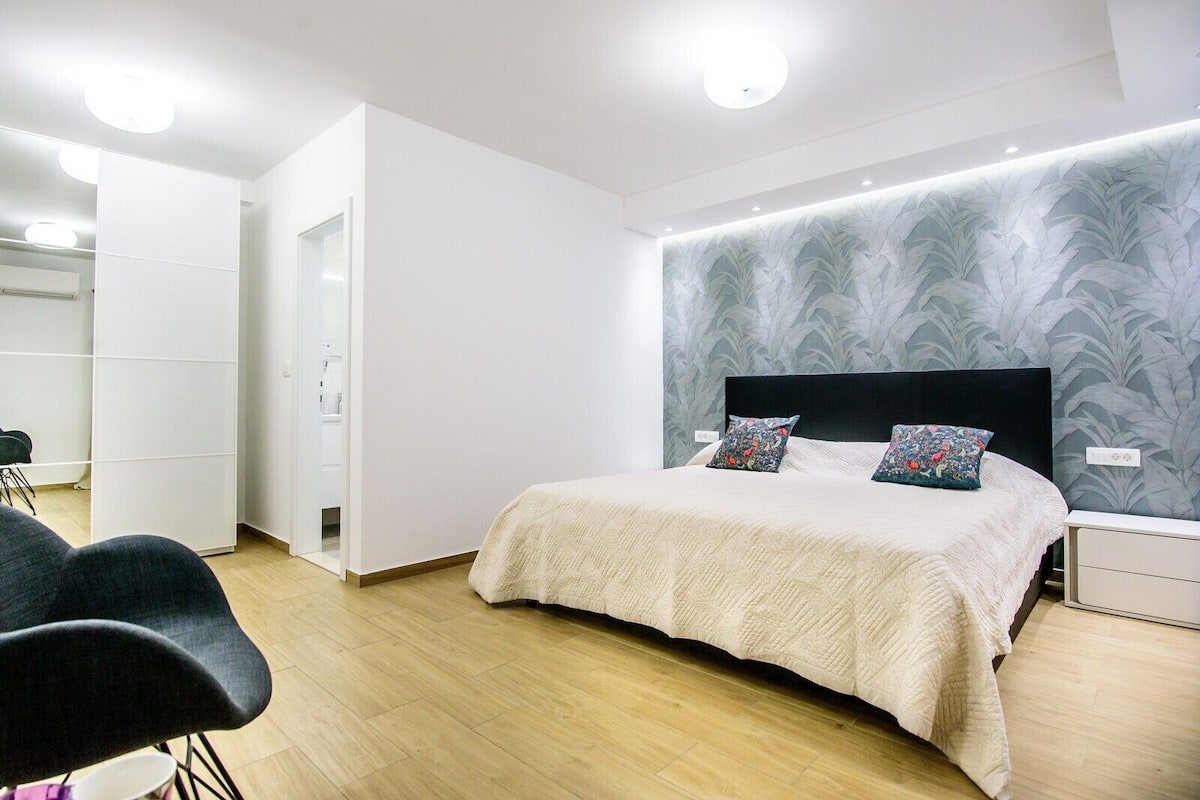 Une chambre à coucher moderne comprenant un lit, des tables de chevet, une armoire et un coin salon.