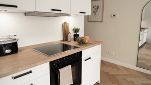 A modern kitchen with white cabinets, a black stove, and a wooden countertop.