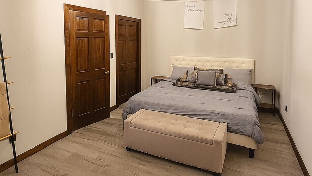 Ein Schlafzimmer mit einem Bett, einer Bank, einer Holztür und einer Lampe.