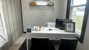 Ein Konferenzraum mit einem weißen Tisch, schwarzen Stühlen, einem Fenster und gerahmten Zertifikaten an der Wand.