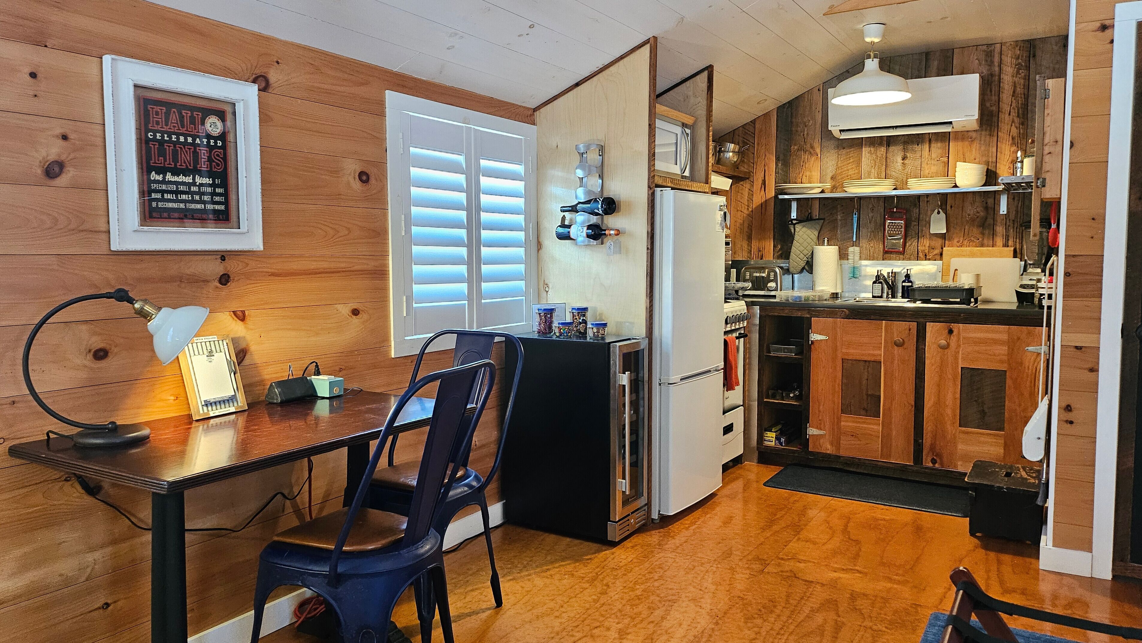 A compact kitchen with wooden cabinets, a refrigerator, a sink, and a dining area with a table and chairs.