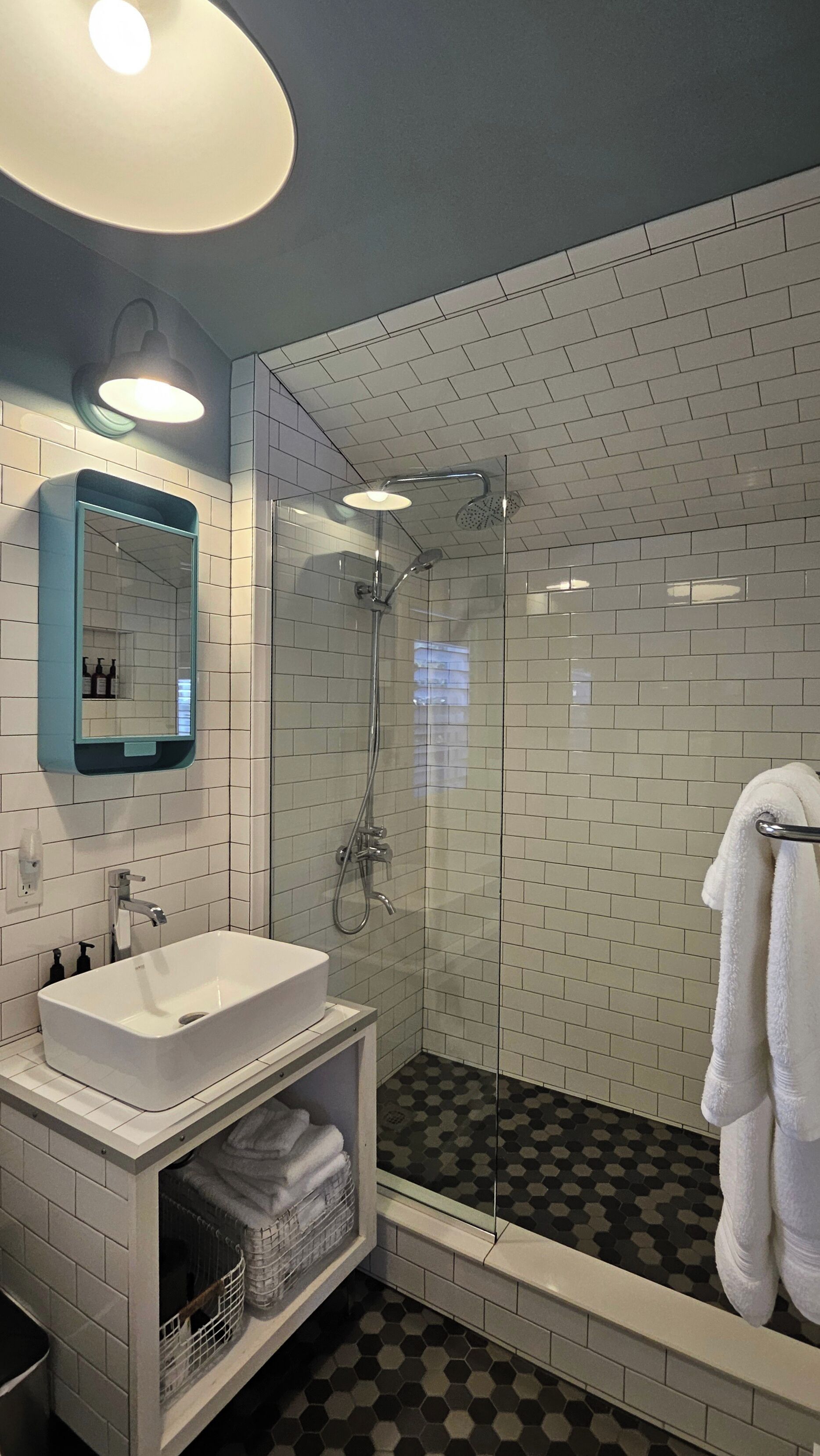 A modern bathroom with a glass-enclosed shower, a white sink, and a mirror with a blue frame.