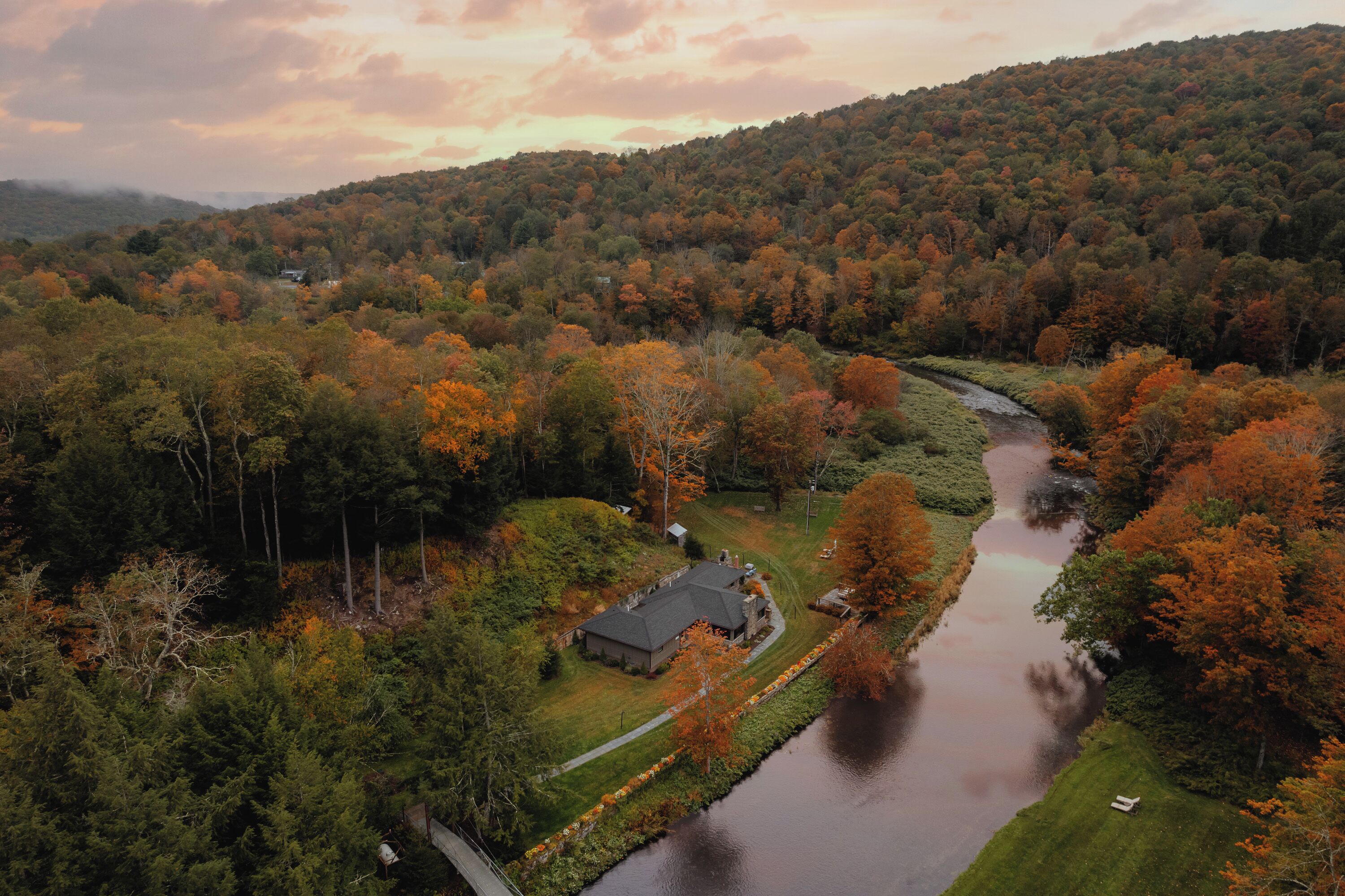 Een huis omringd door een bebost gebied met een rivier erdoor.