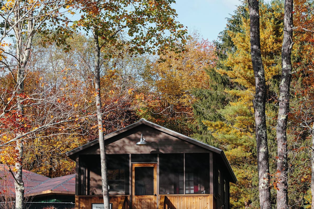 A cabin with a wooden exterior, a porch, and a small staircase leading to the entrance.