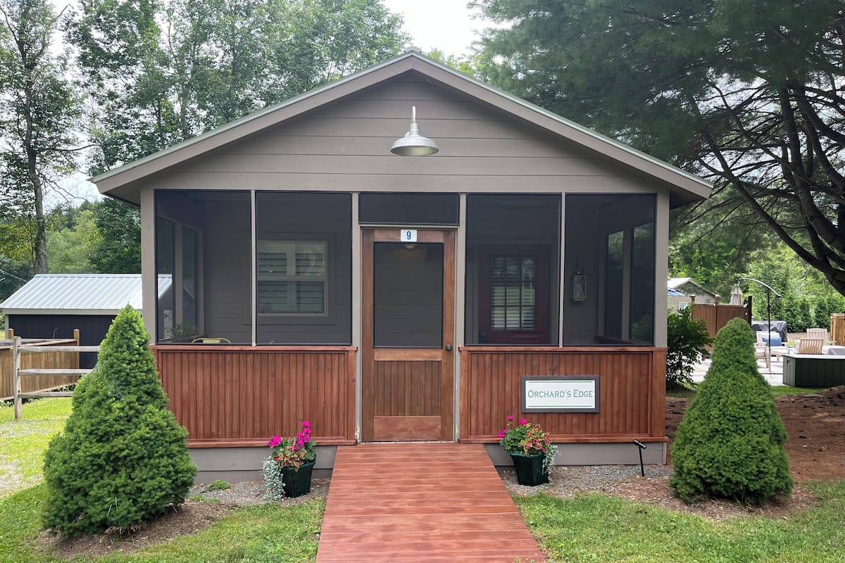 A small, single-story building with a brown exterior, a front door, and a sign reading "Orchard's Edge".