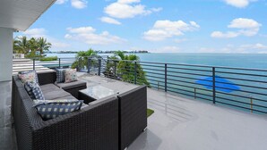 A balcony with wicker furniture and a view of the sea.