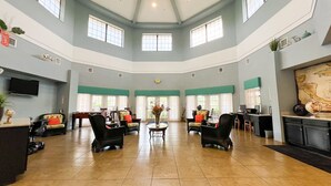 A spacious lobby with high ceilings, multiple seating areas, and large windows allowing natural light.