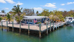 A docked boat, a small building with an American flag, and a wooden pier. - Charming 2-bedroom house in beautiful Marathon with Swim Spa, Dock, Pets Welcome (Marathon)