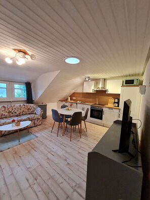 A loft-style living space with a dining area, kitchen, and a sofa.