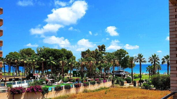 A resort with a pool area, palm trees, and a view of the ocean.
