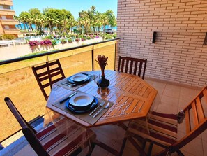 A dining table set outdoors with a view of a pool and palm trees.