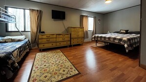 A room with bunk beds, a dresser, a flat-screen TV, and a patterned rug. - Private Serene Cabin (Coudersport)