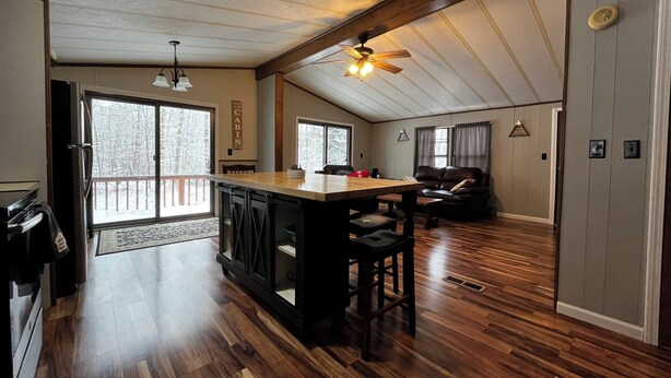 A spacious living area with a wooden floor, a dining table, and a ceiling fan. - Private Serene Cabin (Coudersport)