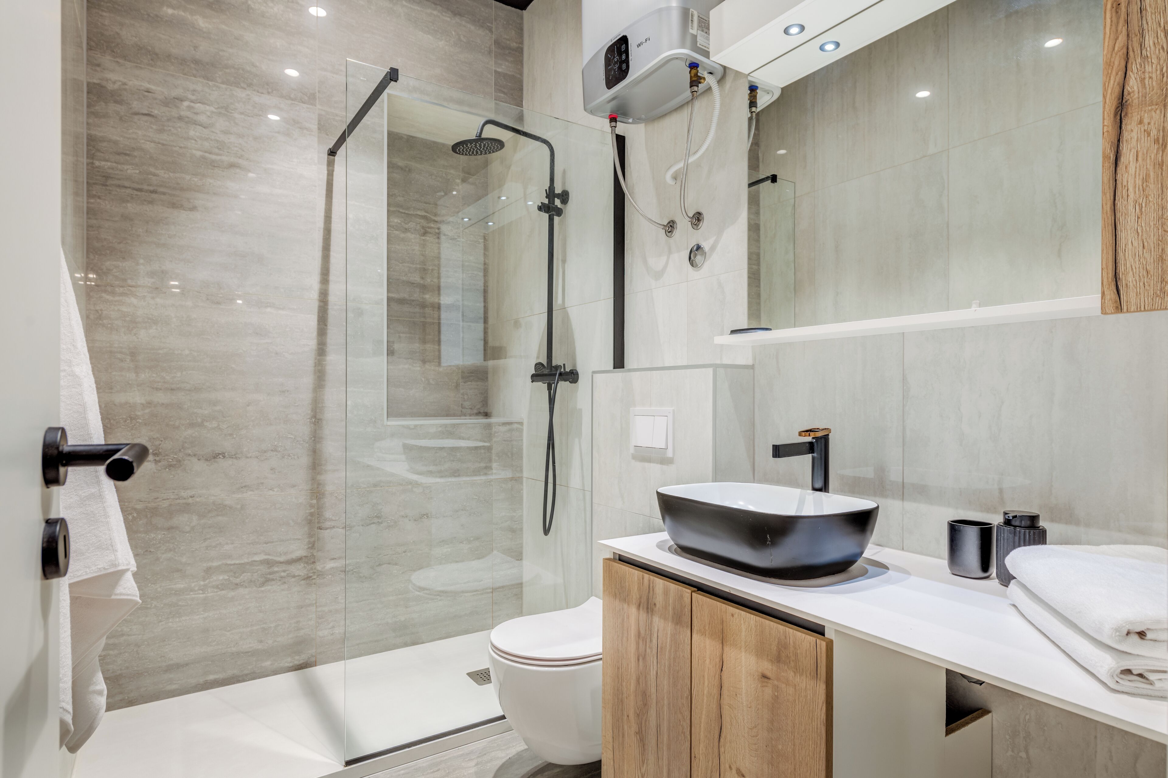 A modern bathroom with a glass-enclosed shower, a white toilet, and a vanity with a black sink.