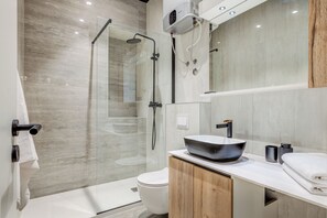 A modern bathroom with a glass-enclosed shower, a white toilet, and a vanity with a black sink. - My Home - Downtown Retreat (Split)