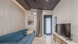 Un salon moderne avec un canapé bleu, un téléviseur à écran plat et un mur en marbre.