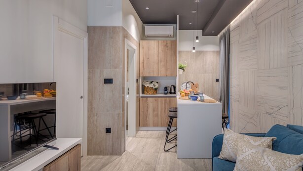 Une cuisine moderne avec des meubles en bois, une cuisinière encastrée et un coin bar avec des tabourets.