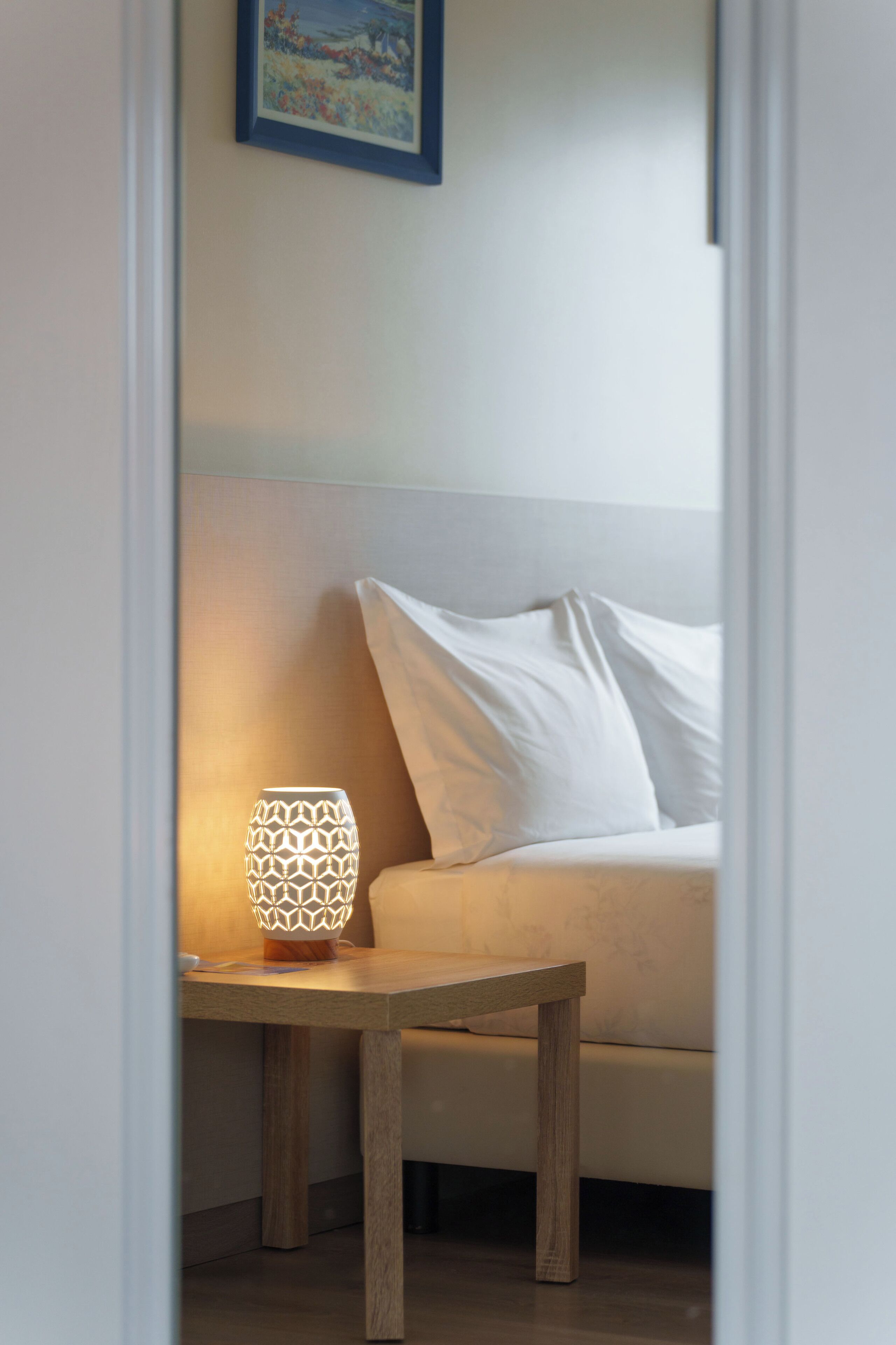 A room with a bed, a nightstand, and a wall-mounted picture.